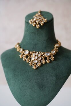 Small delicate floral kundan gold necklace set with jhumka earrings and matching tikka in traditional Indian design