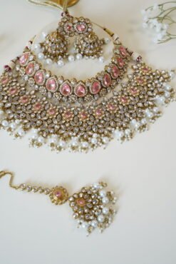 Seyora two-layer South Asian bridal necklace set featuring clear stone and pearl settings with a choker, longer necklace, matching jhumka earrings, and a maang tikka