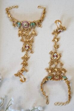 Bridal haathphool (Indian hand harness) in an intricate gold-tone design featuring a central floral motif connected by delicate chains to a statement ring, elegantly draping across the hand for a traditional wedding look