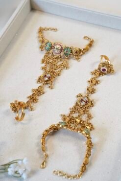 Bridal haathphool (Indian hand harness) in an intricate gold-tone design featuring a central floral motif connected by delicate chains to a statement ring, elegantly draping across the hand for a traditional wedding look