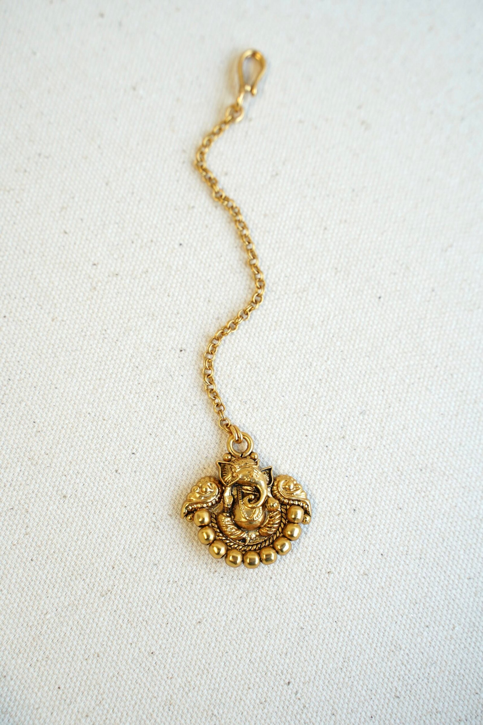 Traditional tikka featuring Lord Ganesha figure, designed for weddings, puja ceremonies, and festive cultural wear.