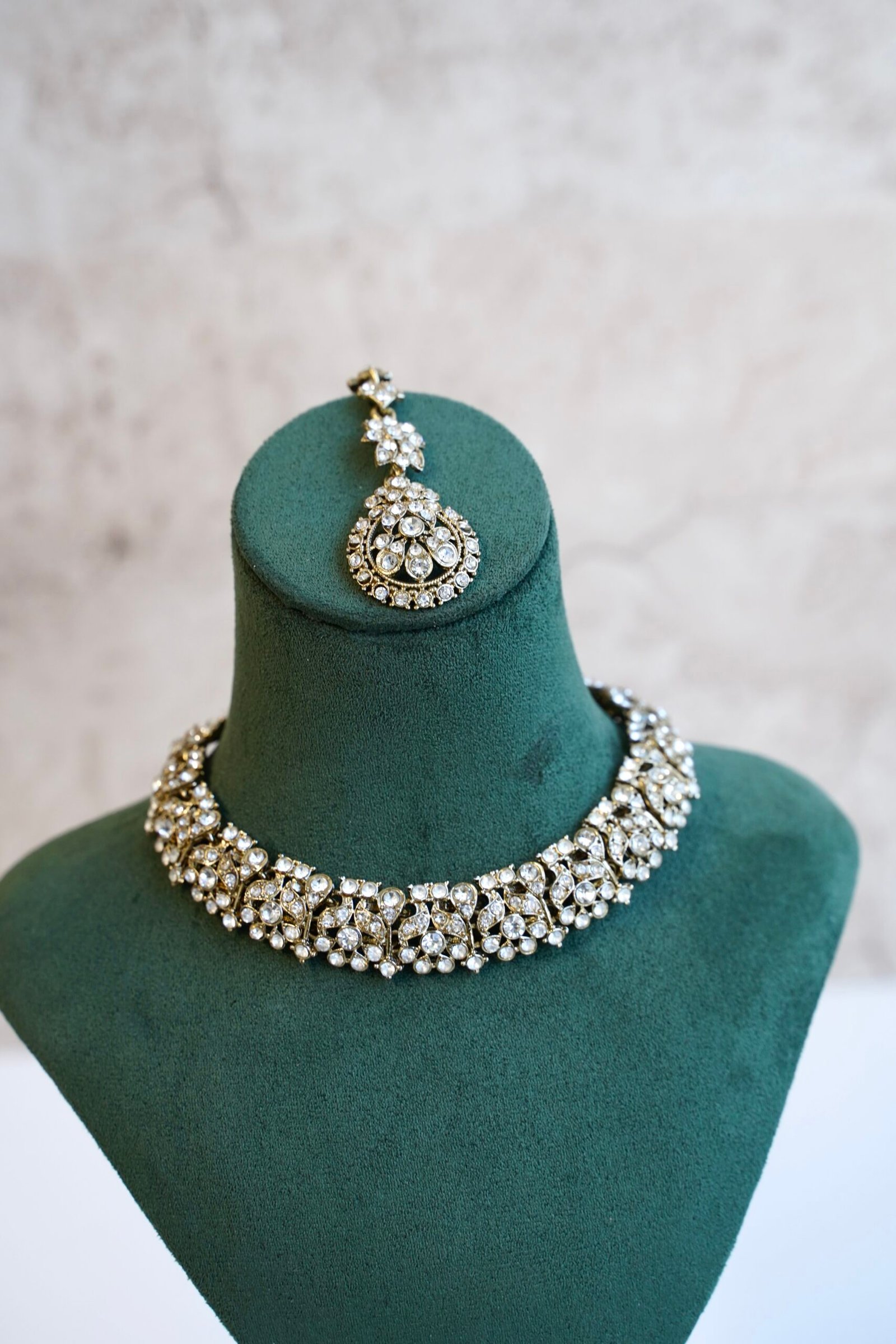Delicate and sparkly small stone necklace set with matching drop earrings and pendant tikka reflecting light.