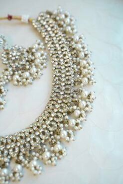 Sparkly flexible zircon necklace featuring flower shaped flower petal drop earrings and a matching pearl-beaded tikka.