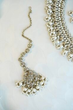 Sparkly flexible zircon necklace featuring flower shaped flower petal drop earrings and a matching pearl-beaded tikka.