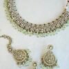 Zoya necklace set featuring clear sparkling stones, hanging pearl beads, matching drop earrings, and a maang tikka.