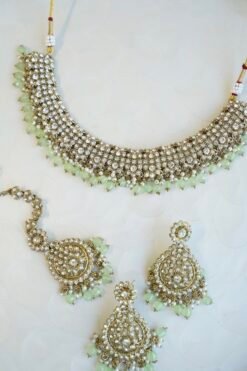 Zoya necklace set featuring clear sparkling stones, hanging pearl beads, matching drop earrings, and a maang tikka.