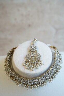 Three piece adjustable sparkling stone choker necklace set with matching earrings and a maang tikka with hanging pearl beads by Seyora Jewels.