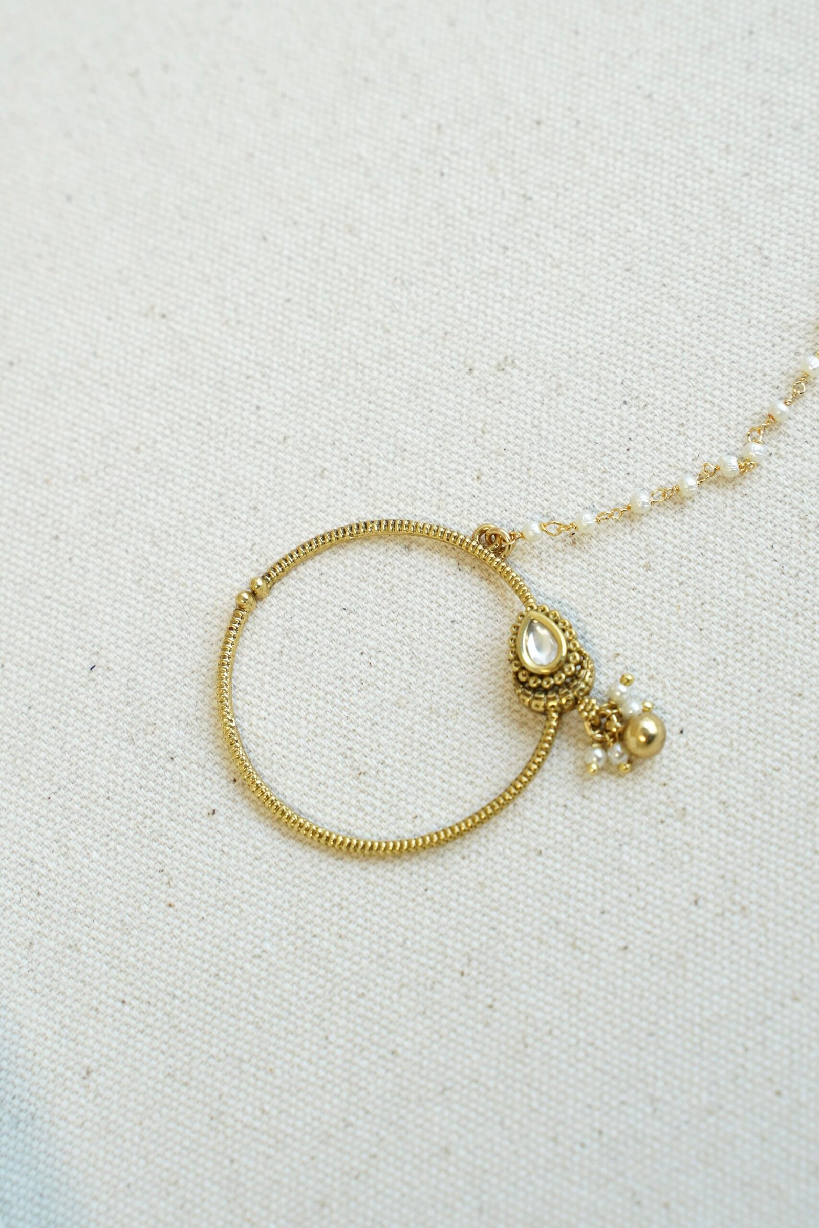 Oversized oval Kundan nath featuring a matte gold finish and a single-layer sleek chain by Seyora Jewels.