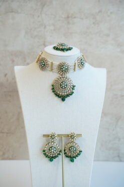 Green artificial Kundan choker necklace featuring a drop pendant and pearl beads, complete with matching earrings and tikka.