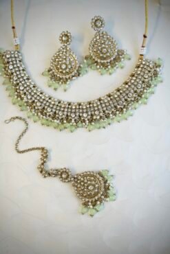 Zoya necklace set featuring clear sparkling stones, hanging pearl beads, matching drop earrings, and a maang tikka.