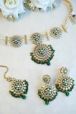 Green artificial Kundan choker necklace featuring a drop pendant and pearl beads, complete with matching earrings and tikka.