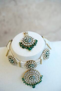 Green artificial Kundan choker necklace featuring a drop pendant and pearl beads, complete with matching earrings and tikka.
