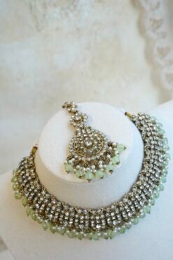 Zoya necklace set in light green with clear stones, hanging light green beads, matching earrings, and tikka