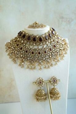Seyora two-layer South Asian bridal necklace set featuring maroon stone and crystal bead settings with a choker, longer necklace, matching jhumka earrings, and a maang tikka
