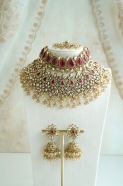 Seyora two-layer South Asian bridal necklace set featuring rani pink stone and pearl settings with a choker, longer necklace, matching jhumka earrings, and a maang tikka.