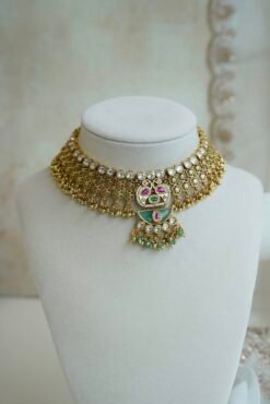 Intricate gold heritage Kundan choker necklace set featuring mint green enamel work, pink accents, and matching earrings on a display stand.