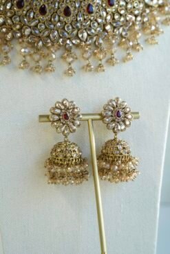 Seyora two-layer South Asian bridal necklace set featuring maroon stone and crystal bead settings with a choker, longer necklace, matching jhumka earrings, and a maang tikka