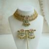 Intricate gold heritage Kundan choker necklace set featuring mint green enamel work, pink accents, and matching earrings on a display stand.