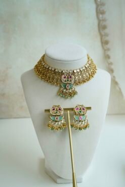Intricate gold heritage Kundan choker necklace set featuring mint green enamel work, pink accents, and matching earrings on a display stand.