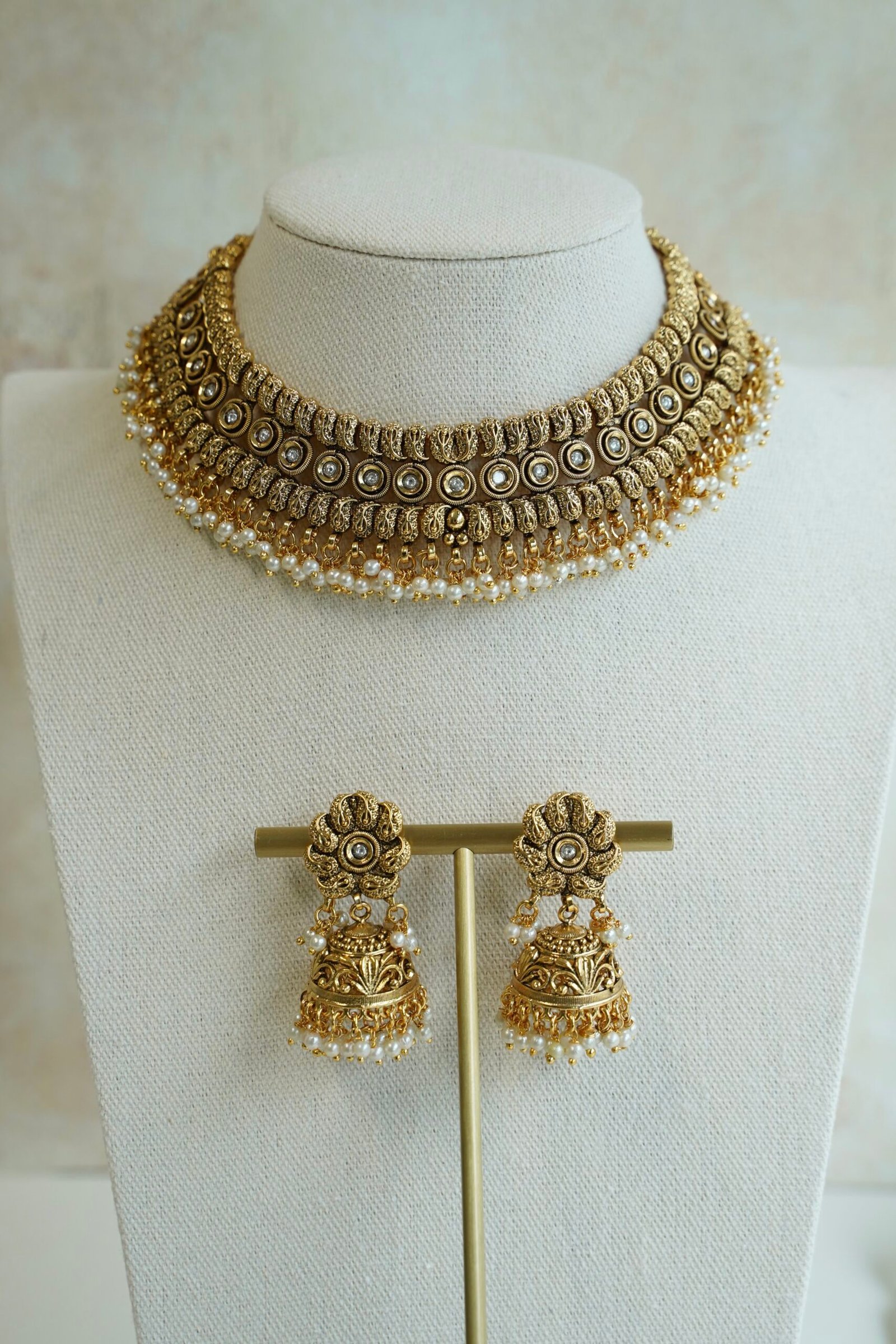 Complete antique matte gold South Asian bridal bridal set including a flexible choker necklace, floral jhumka earrings, and matching maang tikka with pearl drop clusters