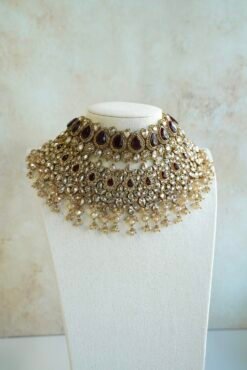 Seyora two-layer South Asian bridal necklace set featuring maroon stone and crystal bead settings with a choker, longer necklace, matching jhumka earrings, and a maang tikka