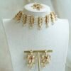 Seyora Jewels pearl choker set featuring detailed Kundan settings with red center stones on matching earrings and maang tikka.