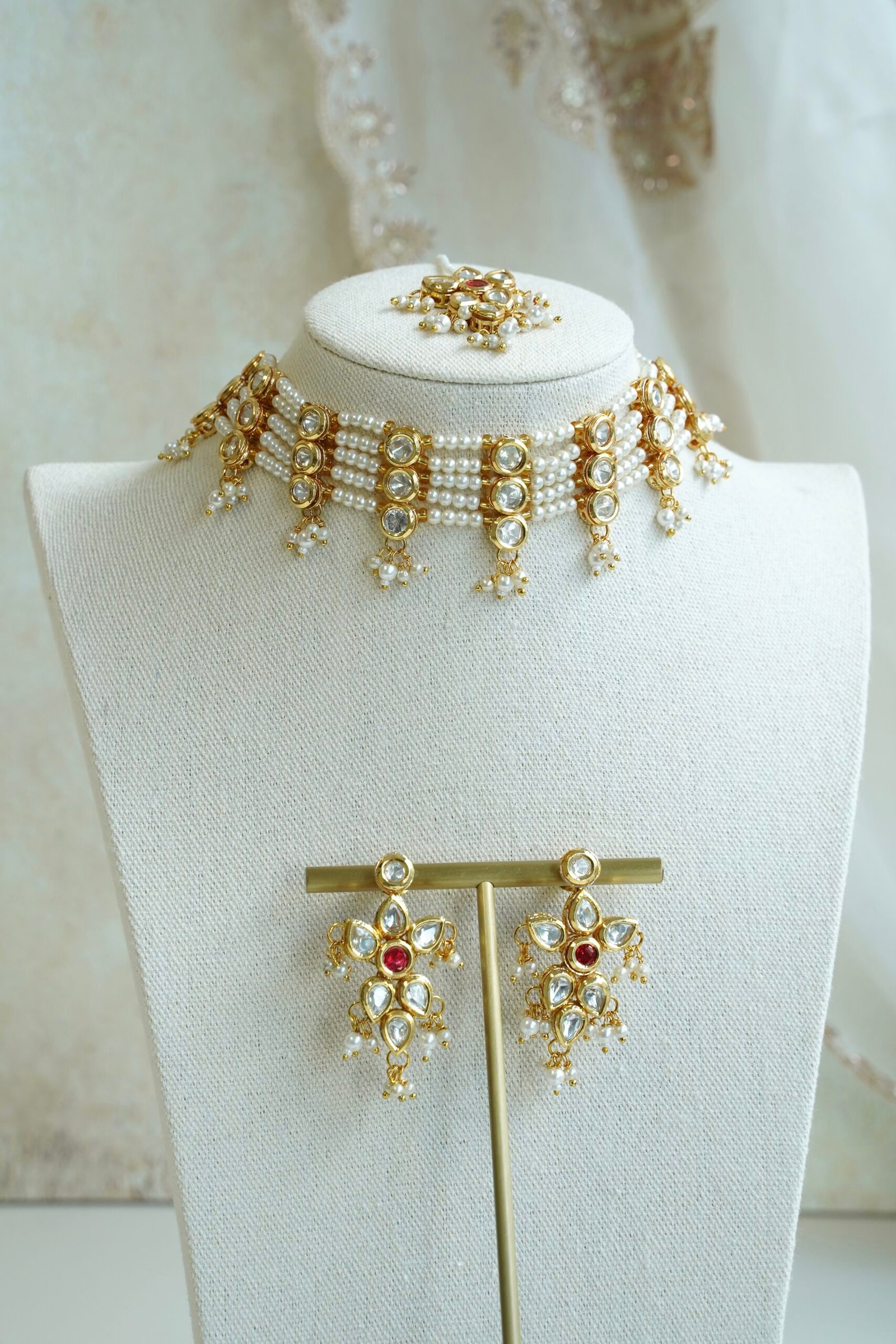 Seyora Jewels pearl choker set featuring detailed Kundan settings with red center stones on matching earrings and maang tikka.