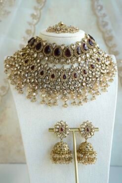 Seyora two-layer South Asian bridal necklace set featuring maroon stone and crystal bead settings with a choker, longer necklace, matching jhumka earrings, and a maang tikka