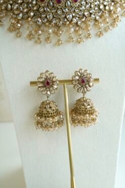 Seyora two-layer South Asian bridal necklace set featuring rani pink stone and pearl settings with a choker, longer necklace, matching jhumka earrings, and a maang tikka.