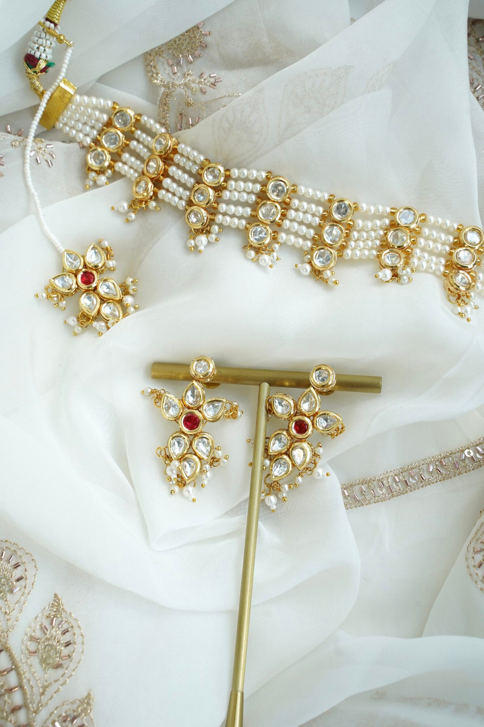 Seyora Jewels pearl choker set featuring detailed Kundan settings with red center stones on matching earrings and maang tikka.