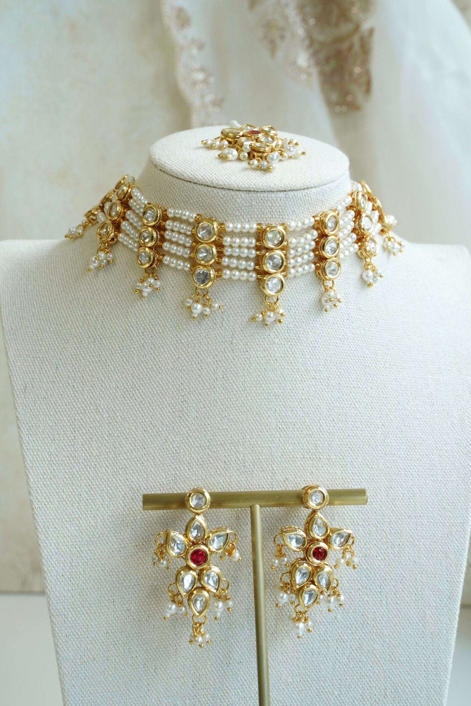 Seyora Jewels pearl choker set featuring detailed Kundan settings with red center stones on matching earrings and maang tikka.