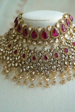Seyora two-layer South Asian bridal necklace set featuring rani pink stone and pearl settings with a choker, longer necklace, matching jhumka earrings, and a maang tikka.