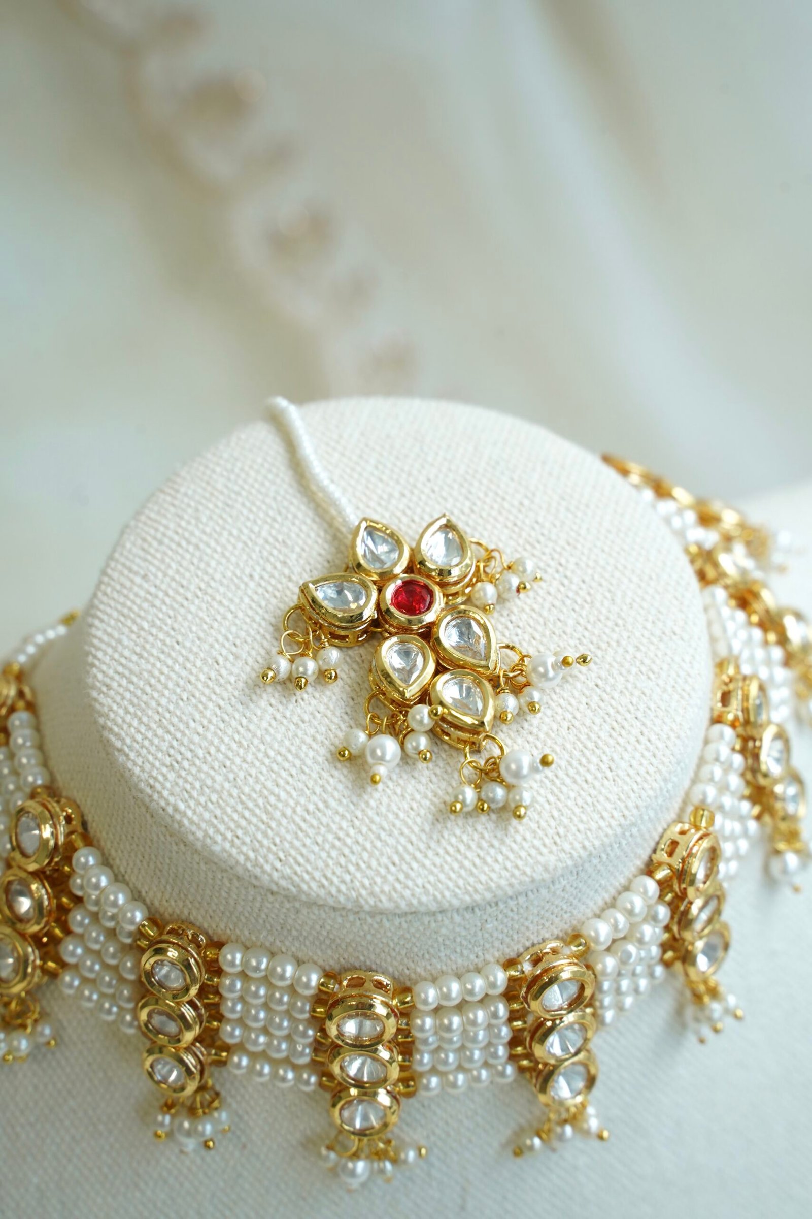 Seyora Jewels pearl choker set featuring detailed Kundan settings with red center stones on matching earrings and maang tikka.