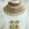 Seyora two-layer South Asian bridal necklace set featuring rani pink stone and pearl settings with a choker, longer necklace, matching jhumka earrings, and a maang tikka.