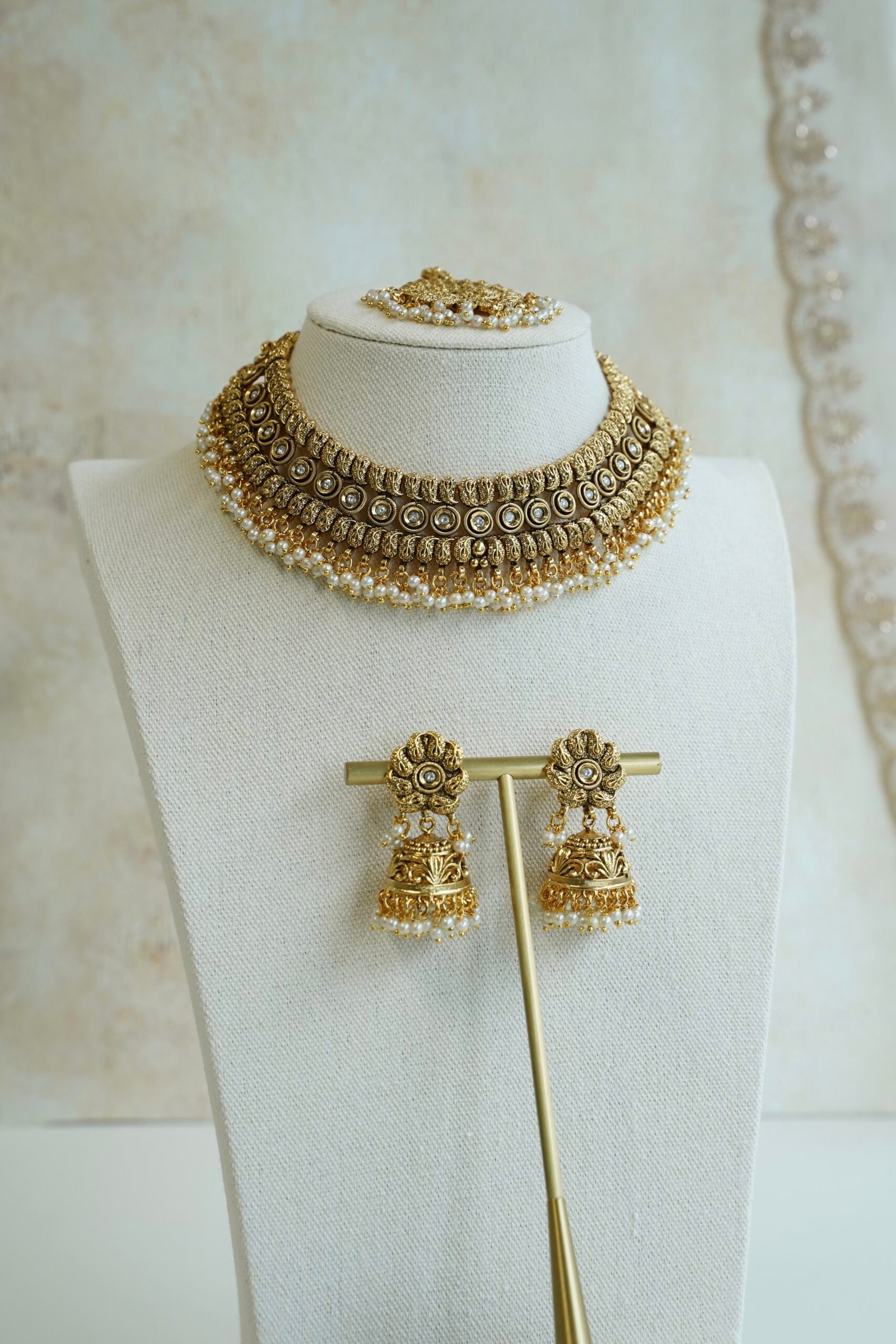 Complete antique matte gold South Asian bridal bridal set including a flexible choker necklace, floral jhumka earrings, and matching maang tikka with pearl drop clusters