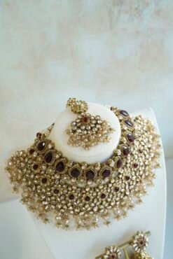 Seyora two-layer South Asian bridal necklace set featuring maroon stone and crystal bead settings with a choker, longer necklace, matching jhumka earrings, and a maang tikka