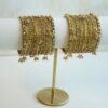 A complete stack of golden kashmiri glass bangles paired with hanging gold ghungroo charms and thin border kadas on each end from Seyora Jewels.