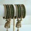 A stack of traditional South Asian glass bangles featuring a prominent central gold jhumka bangle adorned with hanging musical ghungroo beads by Seyora Jewels.