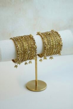 A complete stack of golden kashmiri glass bangles paired with hanging gold ghungroo charms and thin border kadas on each end from Seyora Jewels.
