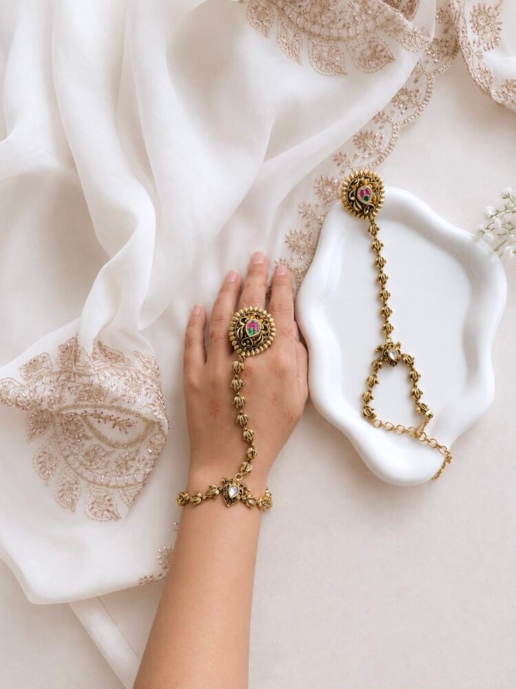 Seyora Jewels Kiran gold-plated Kundan hathpan hand chain featuring an oval rani pink and green finger ring connected to an adjustable wrist chain.