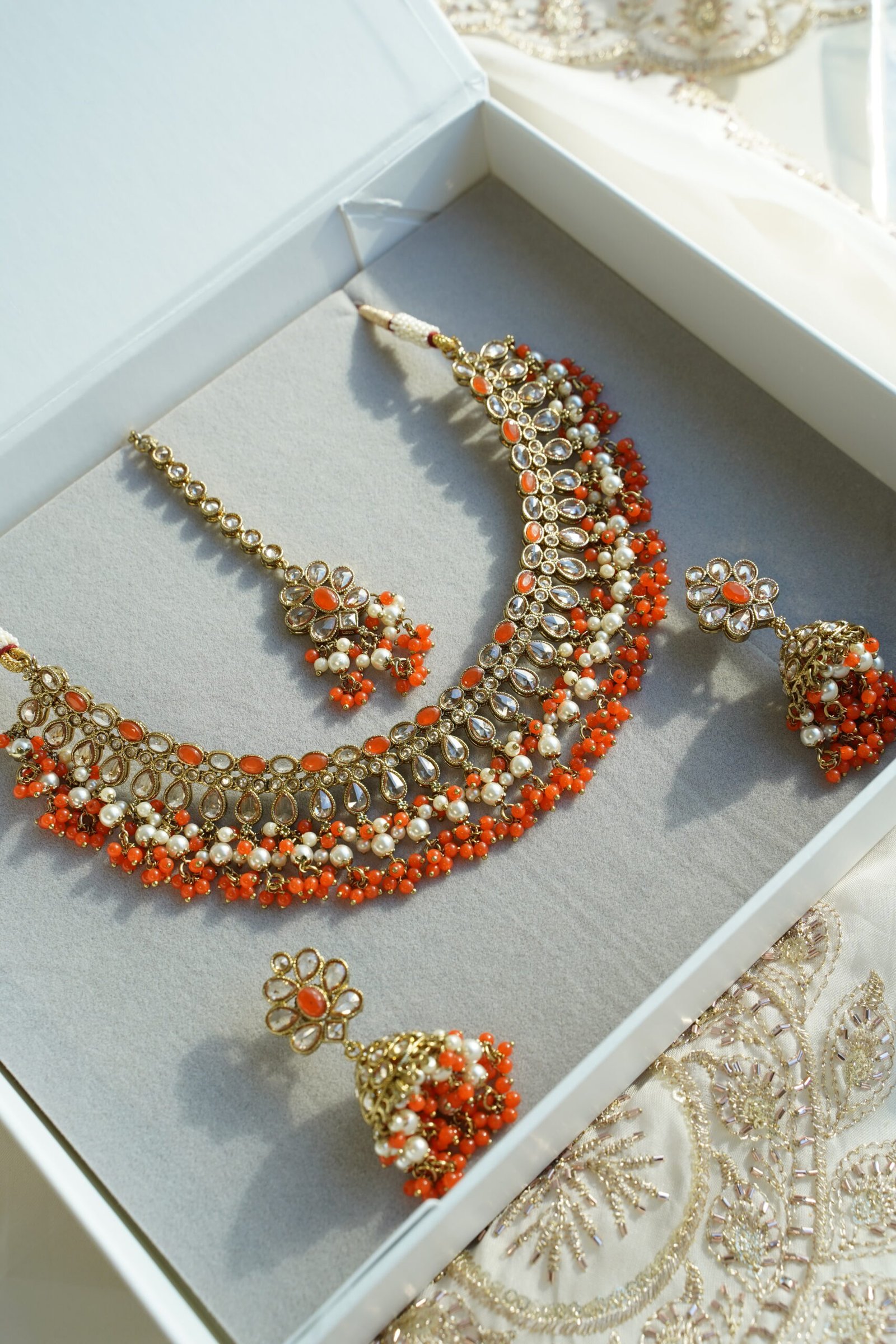 Heer necklace set in orange with antique gold necklace, pearl and orange bead drops, jhumka earrings and tikka displayed in a gift box