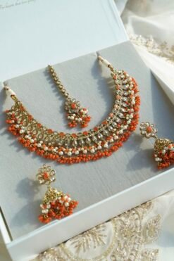 Heer necklace set in orange with antique gold necklace, pearl and orange bead drops, jhumka earrings and tikka displayed in a gift box