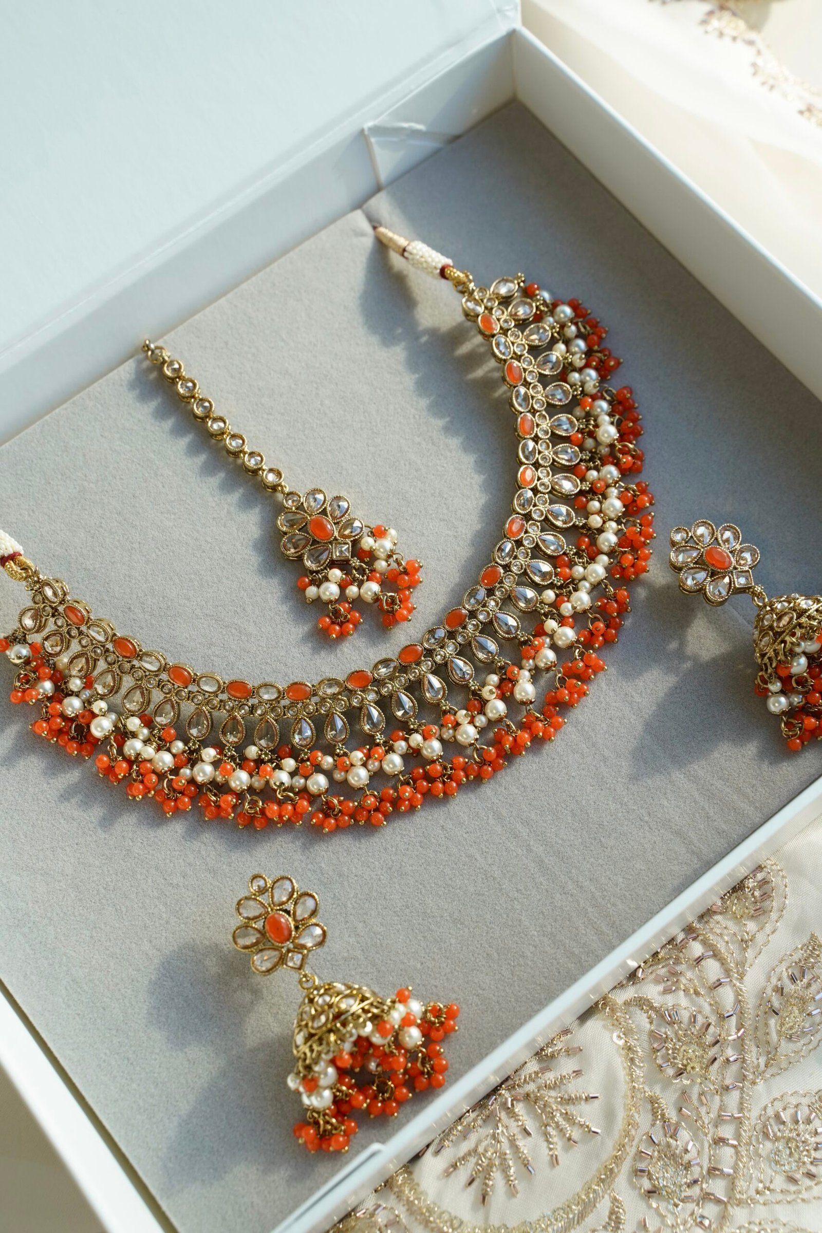 Heer necklace set in orange with antique gold necklace, pearl and orange bead drops, jhumka earrings and tikka displayed in a gift box