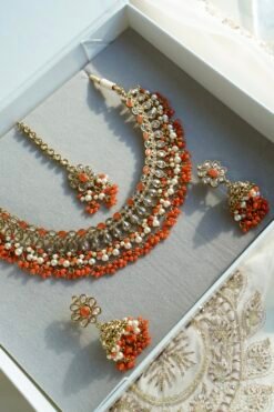 Heer necklace set in orange with antique gold necklace, pearl and orange bead drops, jhumka earrings and tikka displayed in a gift box