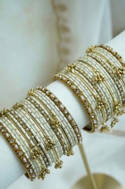 Soft ivory and gold ghungroo bangle set with pearl and stone accents, South Asian festive jewelry