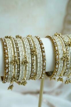 Soft ivory and gold ghungroo bangle set with pearl and stone accents, South Asian festive jewelry