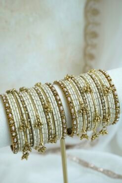 Soft ivory and gold ghungroo bangle set with pearl and stone accents, South Asian festive jewelry