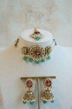 Aaliyah choker set in maroon and green with multi-strand pearl beaded band, antique gold centerpiece, mint green bead drops, jhumka earrings and tikka displayed on a bust