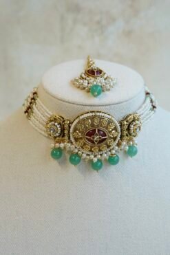 Aaliyah choker set in maroon and green with multi-strand pearl beaded band, antique gold centerpiece, mint green bead drops, jhumka earrings and tikka displayed on a bust