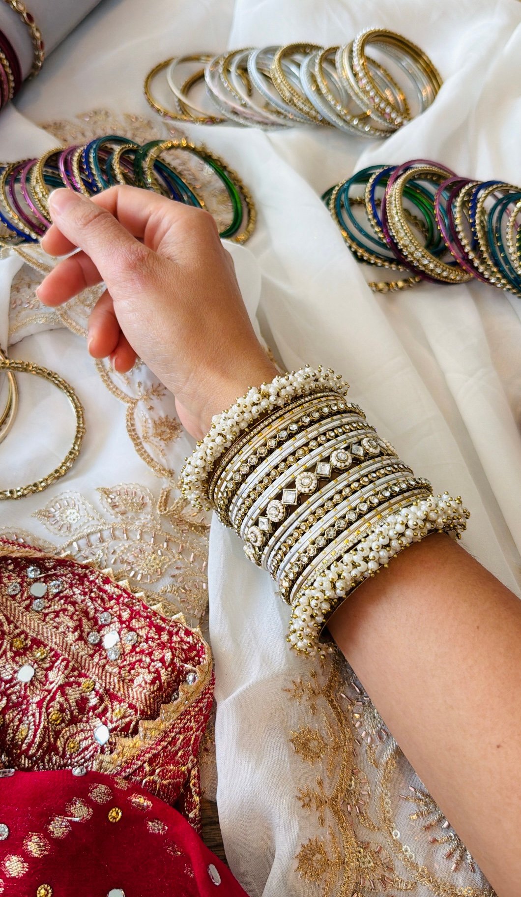 Creame bangle set with gold-tone detailing, clear stones and pearl-style bead edges stacked on a display stand